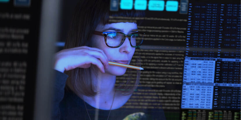 vrouw kijkt geconcentreerd naar verschillende beeldschermen met data